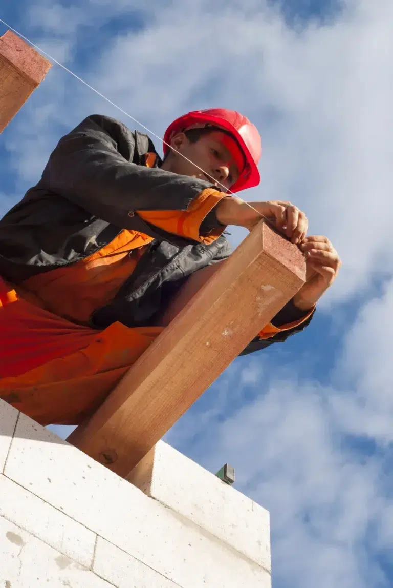ASI Construction roofer on a roof measuring the distance between beams to assist with repair and replacement of a new roof.