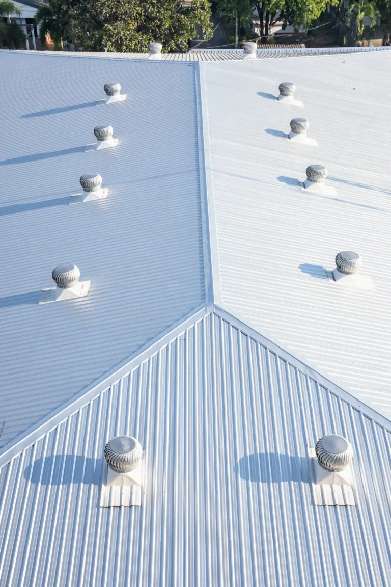 Aerial view of a new white metal slanted roof top installed by ASI Construction on a commercial roof