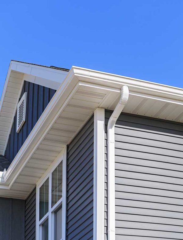Side angle view of a residential home with navy blue siding and new white gutters installed by ASI Construction.