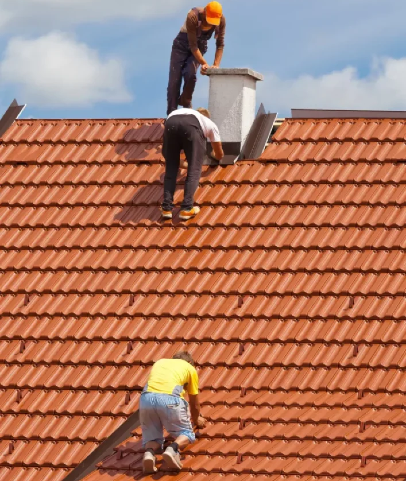 Three ASI Construction workers on roof installing a new roof and waterproof siding alongside the roofs chimney.